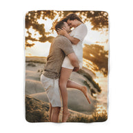 A rectangular photo blanket with a custom printed image of a couple embracing on a beach at sunset, shown against a plain white background.
