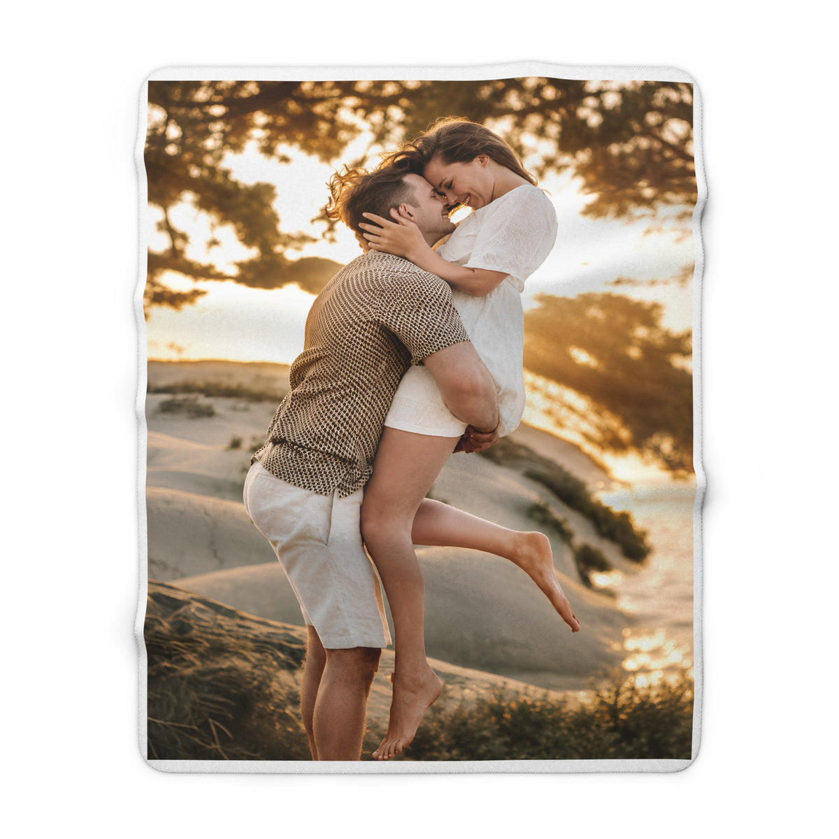 A square fleece blanket featuring a custom printed photo of a couple embracing on a beach at sunset, shown against a plain white background.
