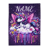 A rectangular personalized purple blanket on a white background, featuring a colorful cartoon unicorn with pink wings, a horn, flowers, butterflies, and dripping paint effects on a purple starry background. The word 'NAME' appears at the top, suggesting a customizable print.