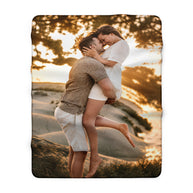 A rectangular photo blanket with rounded corners, featuring a printed image of a couple embracing outdoors at sunset, shown against a plain white background.
