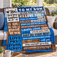 A custom patchwork-style fleece blanket with motivational quotes for a son, draped over a wicker armchair on a porch. The blanket features a mix of blue, brown, beige, and white panels with black text.