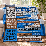 A blue and brown fleece blanket with motivational quotes for a son, draped over a white sofa in a bright living room setting.