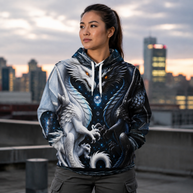 A woman wearing a detailed fantasy hoodie with a white dragon on the left side and a black dragon on the right side, standing on a rooftop with a city skyline at sunset in the background.