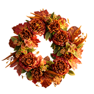 An autumn-themed artificial floral wreath featuring textured orange and red faux roses, maple leaves, and green foliage, isolated on a white background.
