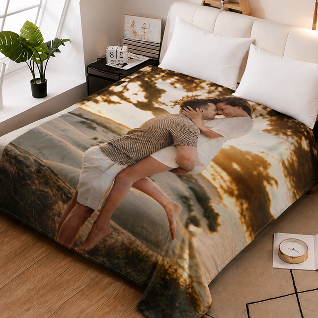 A custom printed blanket featuring a photo of a couple embracing, styled on a bed in a modern bedroom setting with wooden floors, bedside tables, and a potted plant.